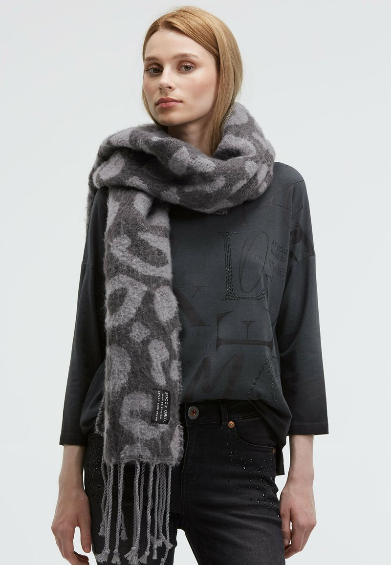 Gray and light gray patterned scarf made of soft material, featuring a fringed edge and a branded label in black.