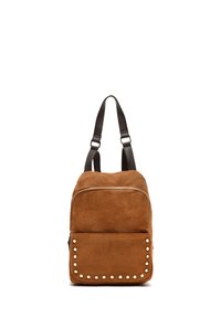 Sac à dos en daim marron avec fermeture éclair, bretelles en cuir noir et poche avant ornée de clous décoratifs blancs.