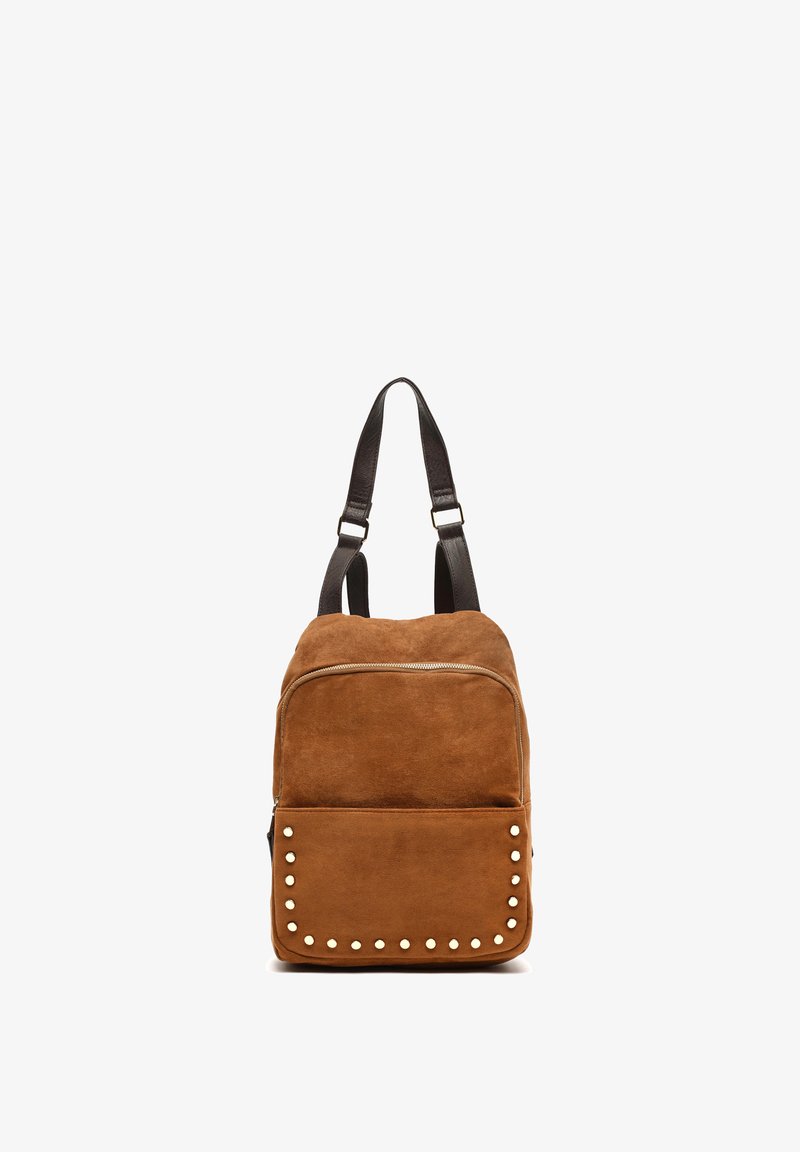 Brauner Wildleder-Rucksack mit einem Reißverschluss, schwarzen Lederträgern und einer Fronttasche, die mit weißen dekorativen Nieten verziert ist.
