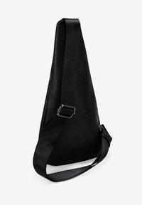 Bolso de piel sintética negra con una forma triangular elegante, correa ajustable y superficie texturizada. Presenta un diseño minimalista sin herrajes.