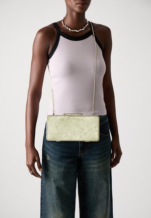 Metallic green rectangular clutch bag with a textured finish, featuring a chain strap and a clasp closure, worn over a fitted top and wide jeans.