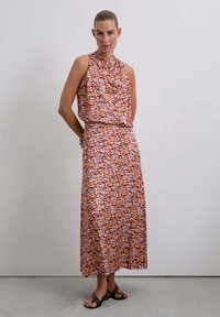Vestido maxi de tela ligera con un escote estilo drapeado, patrones ondulados vibrantes en naranja y rosa, con una cintura ajustada y una falda fluida.
