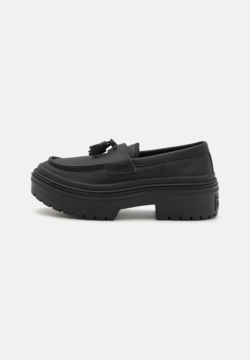 Svart plattform loafers laget av glatt skinn, med rund tå, dekorative dusker og en tykk gummisåle med strukturert mønster.