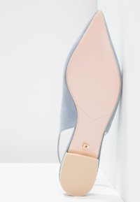 Scarpa con tacco alto in suede blu chiaro, con punta affilata, che mostra una suola beige e una soletta rosa chiaro. Presenta dettagli laterali a taglio. Numero 37.