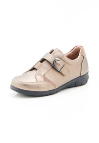Scarpa in pelle beige con finitura testurizzata, presenta una cinghia in velcro e una fibbia, suola in gomma nera, profilo basso e punta arrotondata.