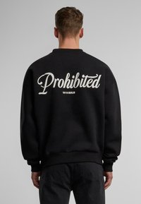 Czarny sweatshirt z białym napisem "Zabronione" oraz "10119 BERLIN" poniżej, o luźnym kroju, z ribbed cuffs i miękką teksturą.