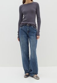 Grau gerippter Langarmoberteil kombiniert mit lockeren blauen Denim-Jeans. Die Schuhe sind silberne Ballerinas mit einer runden Zehenpartie. Einfaches Design und Textur.