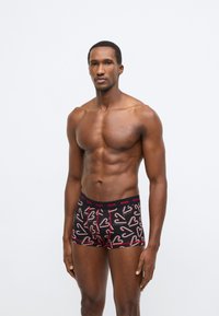 Μαύρα ανδρικά μποξεράκια με κόκκινο μοτίβο καρδιάς από καραμέλα μπαστούνι, με μονόχρωμη κόκκινη ελαστική μέση με λεπτομέρειες λογότυπου και εφαρμοστή γραμμή.