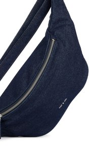 Borsa a tracolla in denim di colore blu scuro con una forma curva. Caratterizzata da una tasca con zip argentata, cuciture a contrasto e dettaglio del logo stampato.