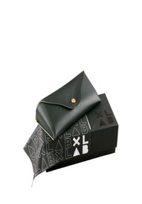 Svart läderplånbok med ett vikbart lock och guldfärgad knappstängning, vilande på en svart låda med vita geometriska logotypmönster.