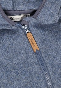 Close-up of blue fleece fabric with gray zipper and tan leather pull tab embossed with brand name "Sterntaler."