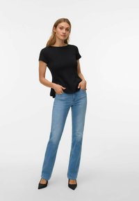 Must must lühikeste varrukatega särk, millel on lihtne ja vormis disain, koos helesiniste sirgete pükstega. Komplekti lõpetavad mustad teravate varvastega kontsakingad.