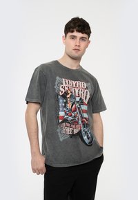 Gray cotton t-shirt with short sleeves, featuring a motorcycle graphic, stars and stripes design, and text stating "Live Free Ride Free."