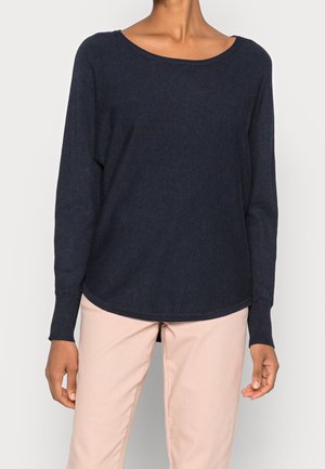 Marineblauem Langarmpullover mit rundem Ausschnitt, strukturiertem Stoff und lockerer Passform. Getragen mit hellrosa Hosen.