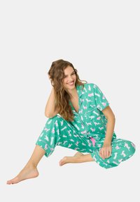 Turkos pyjamas-set med rosa djurmönster, kortärmad topp och lösa byxor. Lättviktsmaterial med en slät textur. Rosa snörning.
