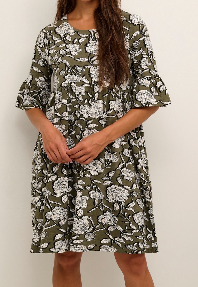 Blumendruckkleid in Olivgrün mit weißen Blumen, kurzen ausgestellten Ärmeln und einem lockeren, knielangen Design. Weiche Stoffstruktur.
