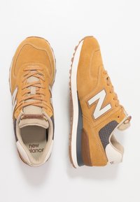 Oranžovo-hnědé semišové tenisky s síťovými akcenty, béžovými tkaničkami a bílým logem "N". Obsahují gumové podrážky pro lepší přilnavost a polstrované límce.