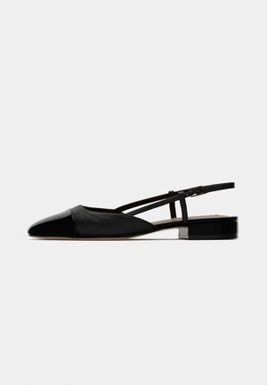 Ballerines noires en cuir avec un bout pointu, un dessus fermé et une sangle ajustable à la cheville. Elles présentent un petit talon carré. Texture lisse.
