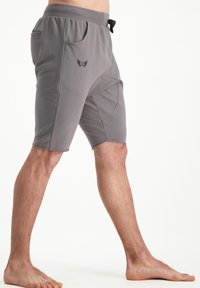 Shorts gris en tissu doux avec une taille élastique et un cordon de serrage, comprenant des poches latérales et un petit logo à l'avant.