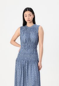 Blue floral dress with a smocked bodice and pleated details. Features sleeveless design and a textured fabric with a flowing skirt.