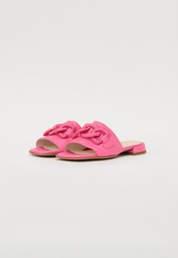 Pink faux leather slide sandals with an open toe, featuring a woven detail on the strap and a small block heel.