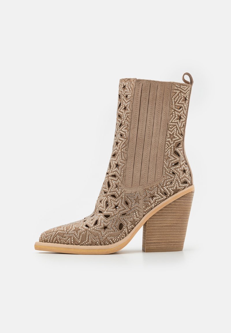 High-heeled boot in light brown suede with cut-out star pattern, textured sides, and a stacked wooden heel. Features a rounded toe design.