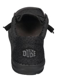 Scarpa slip-on nera tessuta con suola in gomma, dotata di un linguetta sul retro e del logo "HEY DUDE" sul tallone. Design semplice e funzionale.