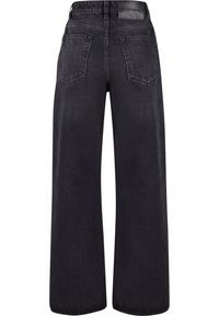 Jean noir à jambes larges avec taille haute, poches arrière, passants pour ceinture et une étiquette en cuir de la marque sur la ceinture.