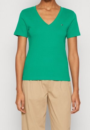 Groen V-hals T-shirt van zacht katoen, met korte mouwen en een klein logo op de linkerbuste. Gecombineerd met licht beige broek.