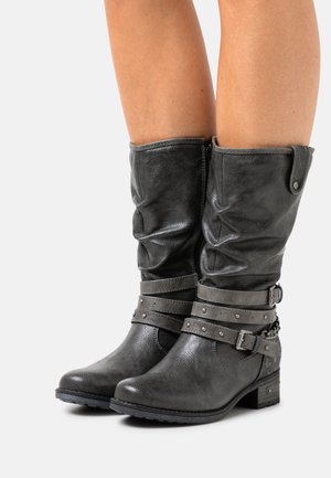 Gray, slouchy leather boots with a round toe, accented by two studded straps and a small chain detail on the heel. Block heel.