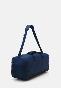 Mala de duffle azul com um fundo texturizado, material em tecido, alça ajustável e duas pegas; inclui um bolso lateral em malha.