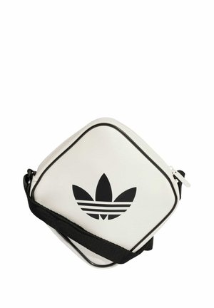 Vit syntetisk crossbody-väska med svarta accenter, försedd med en framträdande svart logotyp med tre ränder och justerbar rem. Fyrkantig form.