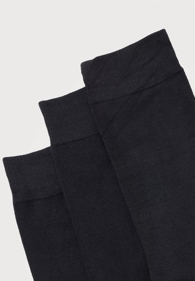 Τρεις μαύρες κάλτσες πληρώματος με ραβδωτές μανσέτες στοιβαγμένες διαγώνια σε λευκό φόντο.