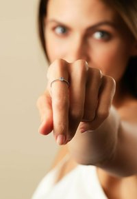 Silverring med en delikat band och en liten blå sten, bärs på ett finger som pekar framåt. Slät yta och minimalistisk design.