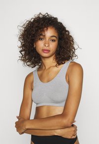 Bralette de algodón gris con escote redondeado y tirantes anchos, que presenta una textura suave y un diseño ajustado.
