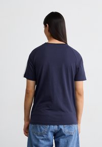 Marineblå bomulds-T-shirt med korte ærmer og en klassisk rund halsudskæring, der har en glat tekstur og et simpelt design.