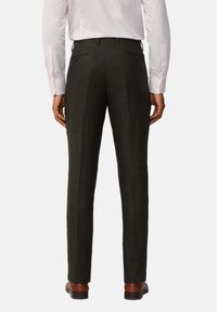 Pantaloni sartoriali verde oliva scuro, con taglio dritto, texture sottile e due tasche posteriori, abbinati a scarpe in pelle marrone.