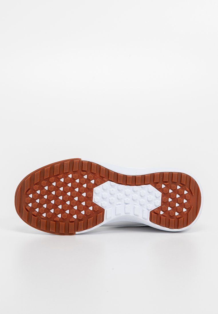 Suela de una zapatilla blanca con suela de goma marrón que presenta patrones hexagonales y rectangulares para mayor agarre sobre un fondo blanco.