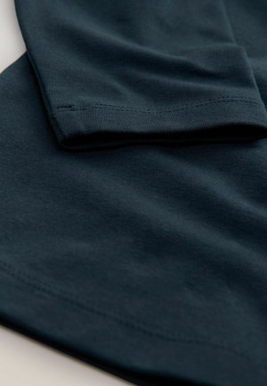 Dunkelblauer Baumwollstoff, eng gefasst, zeigt die glatte Textur, Nahtdetails und Falten der Hemdsärmel. Minimalistisches Design.