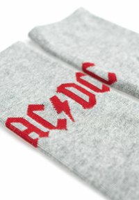 Calzini grigi con scritte "AC/DC" rosse in un carattere audace. Tessuto morbido con texture a costine. Il design include accenti a forma di fulmine nelle scritte.