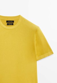 Short-sleeve yellow T-shirt made of soft cotton, featuring a ribbed crew neckline and clean hem edges. Labels are visible inside.
