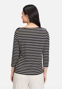 Czarna i biała, w paski, długozmienna bluzka z szerokim dekoltem, charakteryzująca się luźnym krojem i miękkim materiałem, pokazana od tyłu.