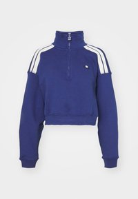 Felpa blu tagliata con colletto alto, strisce bianche sulle spalle e un piccolo logo sul petto. Realizzata in un morbido tessuto testurizzato.