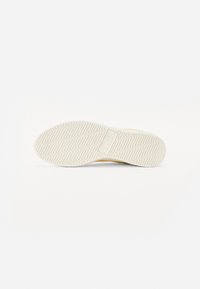 Podešev z off-white gumy s cik-cak vzorem. Obsahuje centrální logo box a hladké okraje, navržena pro trakci a trvanlivost.