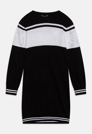 Sort strikket kjole med lange ærmer, hvide horisontale striber og "GUESS"-logo med rhinsten på brystet og de øverste ærmer.