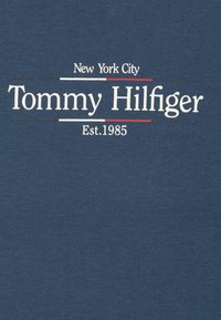 Námořnická modrá bavlněná tričko s bílým textem: "New York City," "Tommy Hilfiger" a "Est.1985," s červenými a černými akcentními linkami.