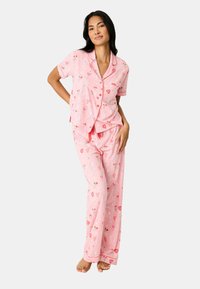 Roze pyjamastel met korte mouwen, versierd met hart- en bloempatronen, met een knoopsluiting bovenstuk en broek met elastische taille. Zachte stofweefsel.