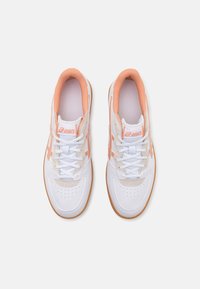 Vita sportskor med persikofärgade detaljer, med en slät läderöverdel, perforerad tåbox och gummisula med texturerad yta.