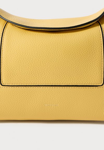 Dzeltena teksturēta ādas soma ar pārsega aizdari un melnām apdares detaļām, priekšpusē redzams izspiedums ar zīmola nosaukumu "Wandler".