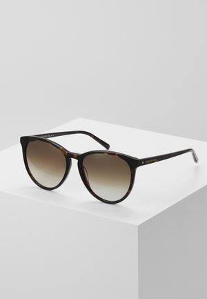 Ochelari de soare cu ramă din plastic cu model țestoasă și lentile maronii cu gradient. Prezintă o formă rotundă de tip cat-eye și accente aurii discrete.